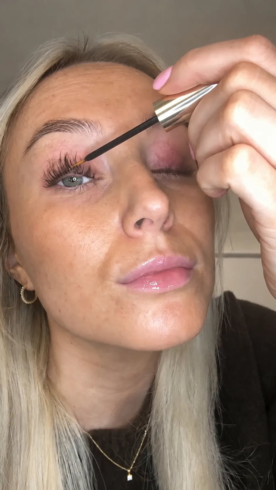 Fine brush applying lash serum along the lash line